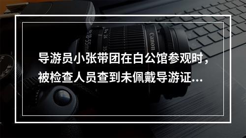 导游员小张带团在白公馆参观时，被检查人员查到未佩戴导游证，